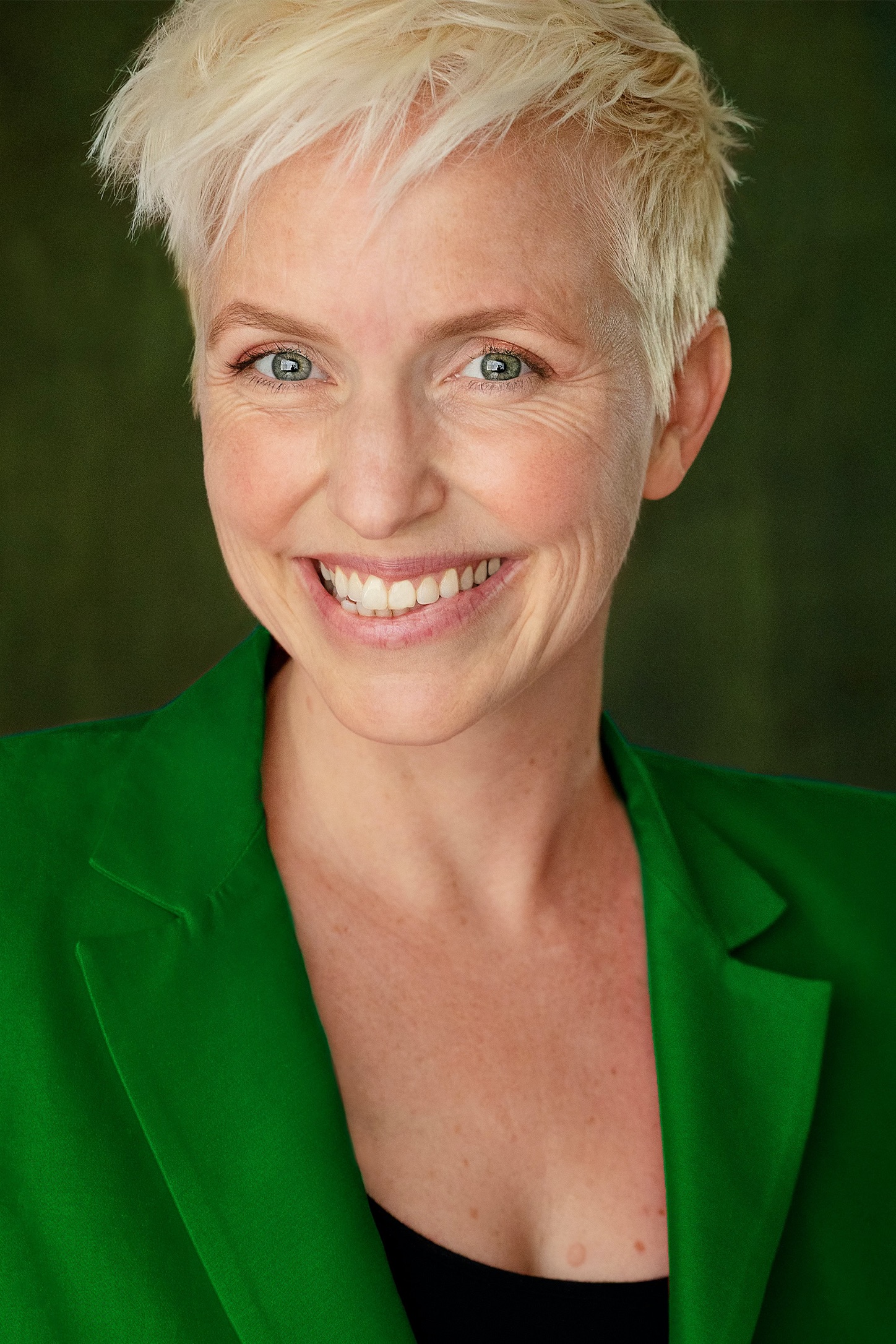 Sonja is smiling at the camera and wearing a green blazer.